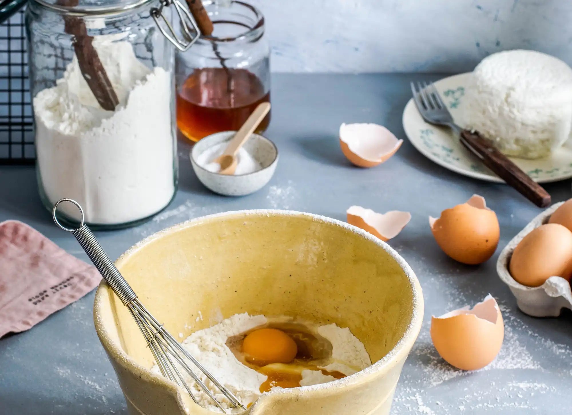 delightfully messy baking station with honey, flour, and a bowl of flour and eggs