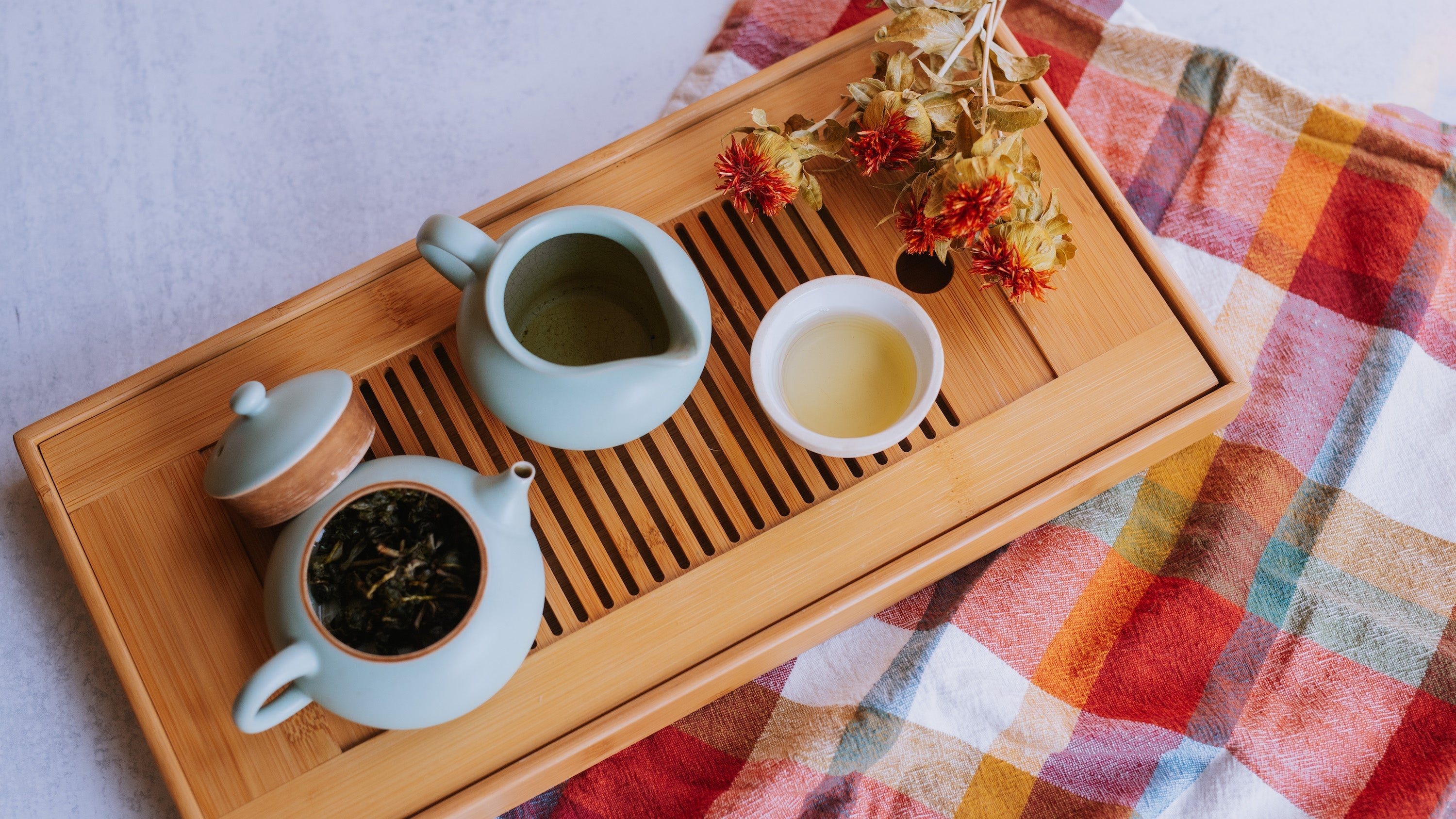 tea boat with small pancake teapot of taiwanese oolong leaves, small pitcher, and small cup of brewed taiwanese oolong
