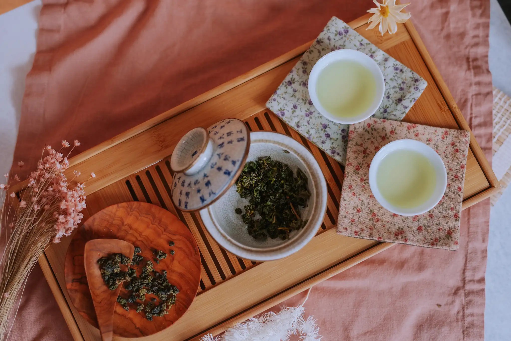 gongfu cha ceremony tea preparation of a lightly oxidized Taiwanese oolong with a background of pink linens