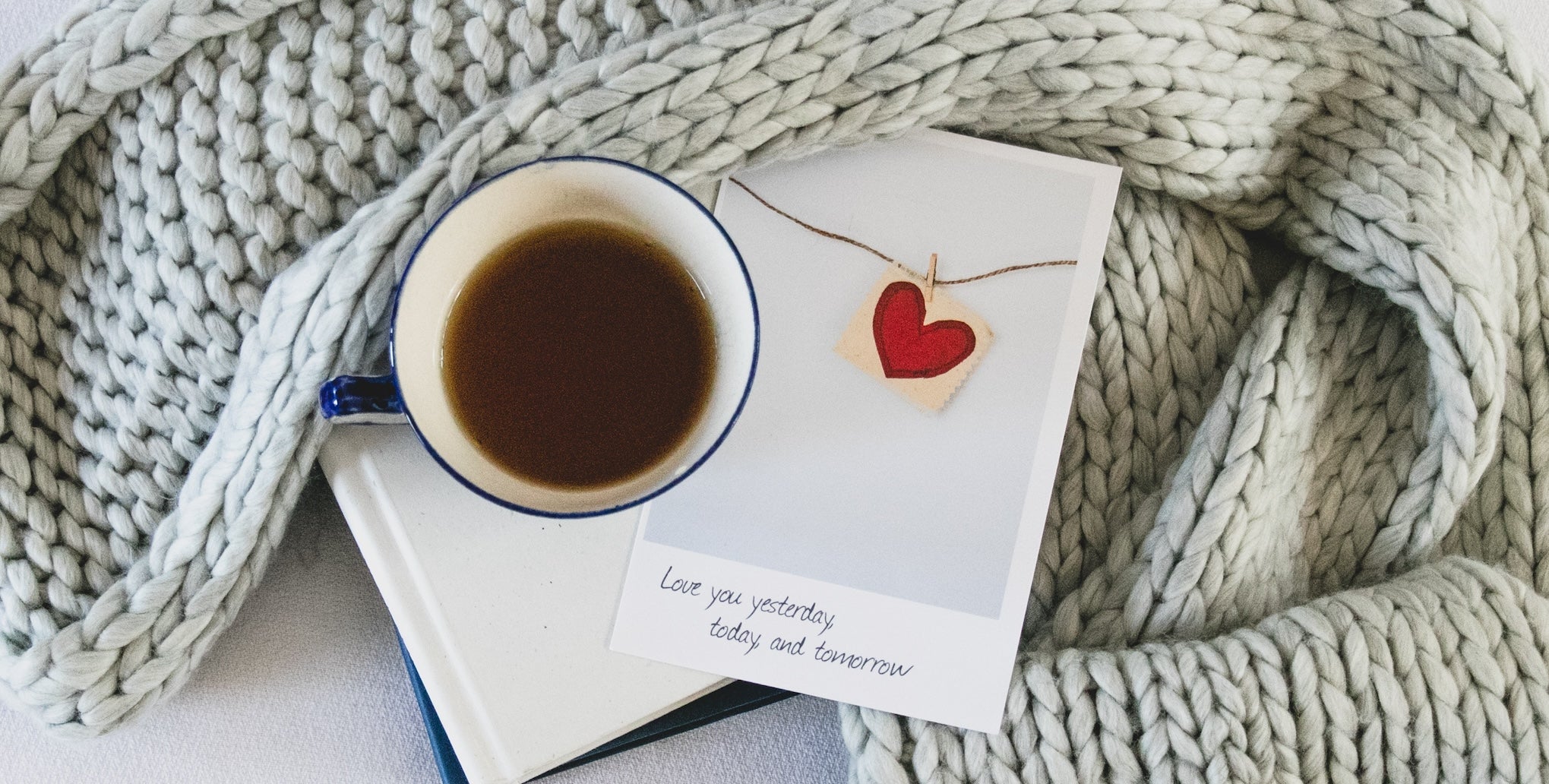 blanket with book, mug of tea, and valentine's card