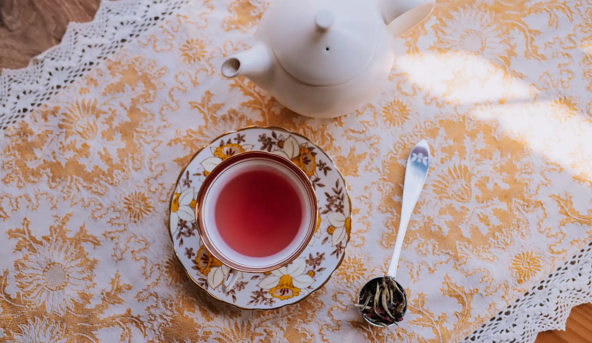 canfield in red fruit scented tea in a vintage teacup on a yellow and white patterned tablecloth