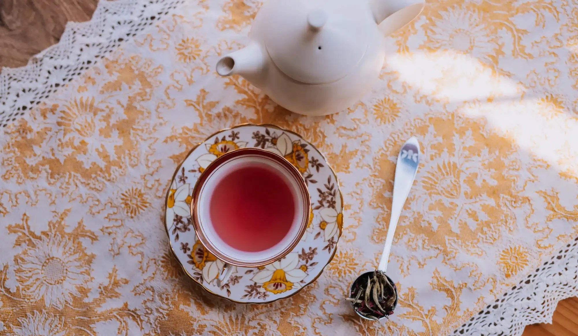 canfield in red fruit scented tea in a vintage teacup on a yellow and white patterned tablecloth