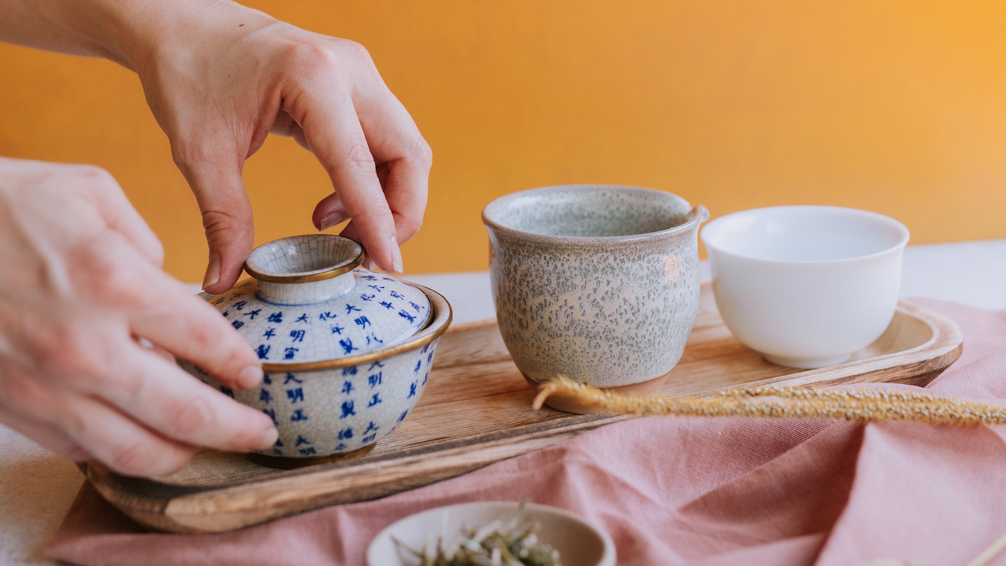 two hands adjusting gaiwan lid in preparation for brewing white tea