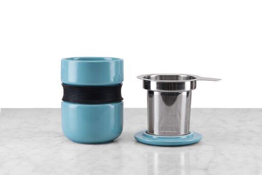 teal asian-inspired tea mug with curved silicone grip sitting next to its included infuser and lid/infuser holder