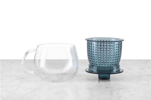 glass tea mug sitting next to blue infuser and lid
