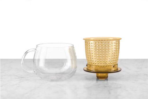 glass mug sitting next to yellow infuser basket sitting on matching top/infuser rest