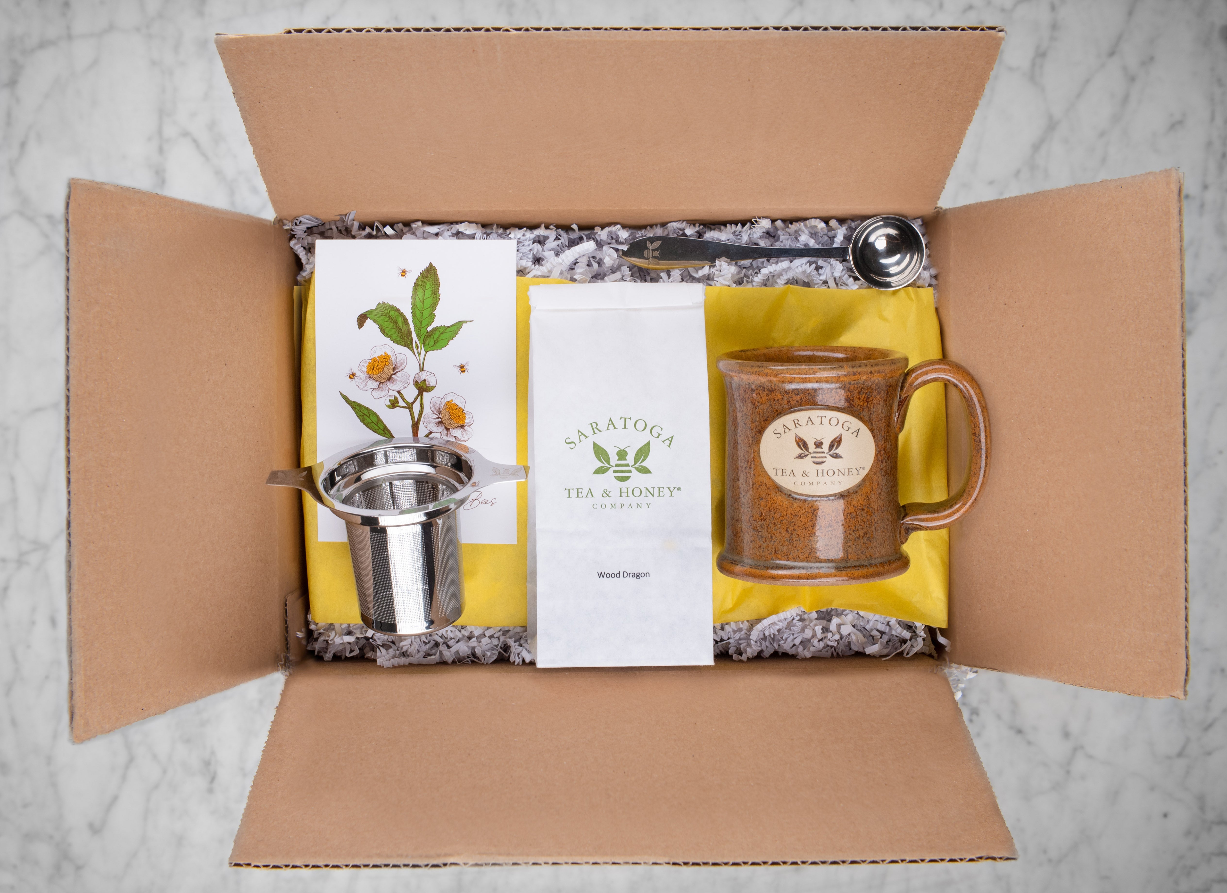gift box with adirondack themed tea gifts including saratoga tea and honey bee tea infuser, wood dragon oolong tea, saratoga tea and honey branded stoneware mug, gift note, and perfect tea scoop