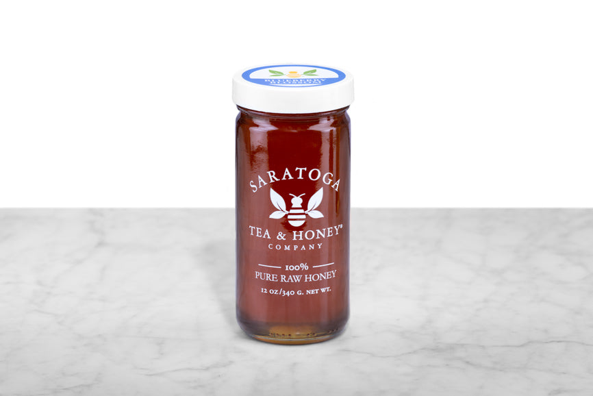 Rich, dark-amber Blueberry Blossom Honey displayed in a 12oz cylindrical glass jar with a white lid. The logo and the words: "100% Pure Raw Honey" are printed on the jar.
