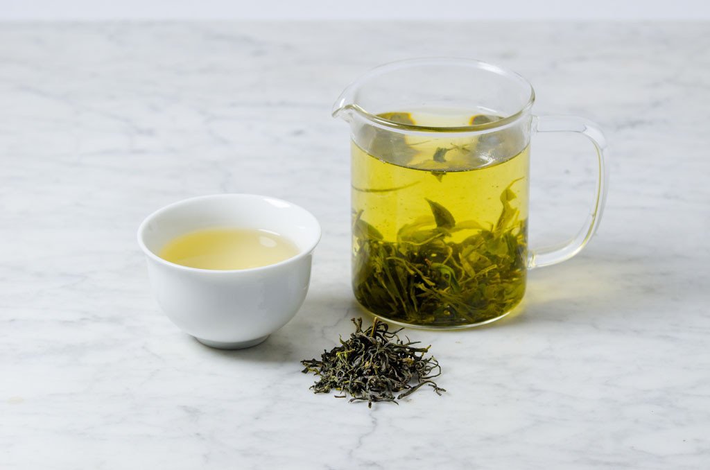 Loose leaf green tea from China brewed in a glass infuser and white cup