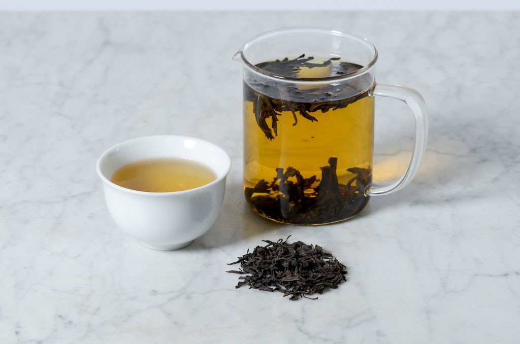 Da Hong Pao oolong loose leaf tea steeped in a glass infuser and poured into a white cup