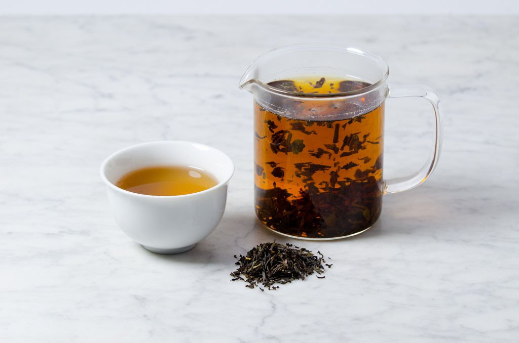 organic loose leaf earl grey tea in a white cup and glass infuser