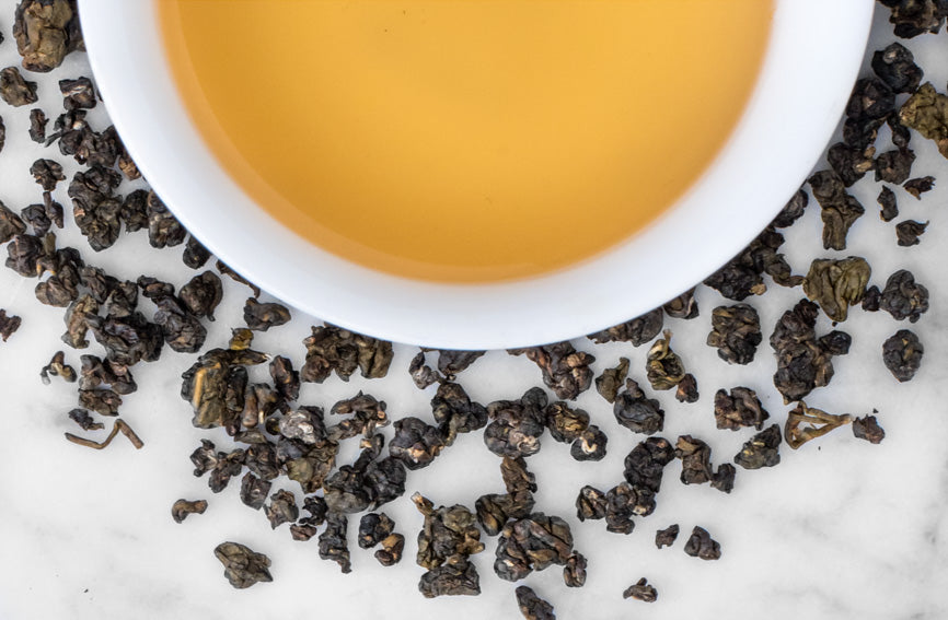 Guei Fei oolong beads around a brewed cup