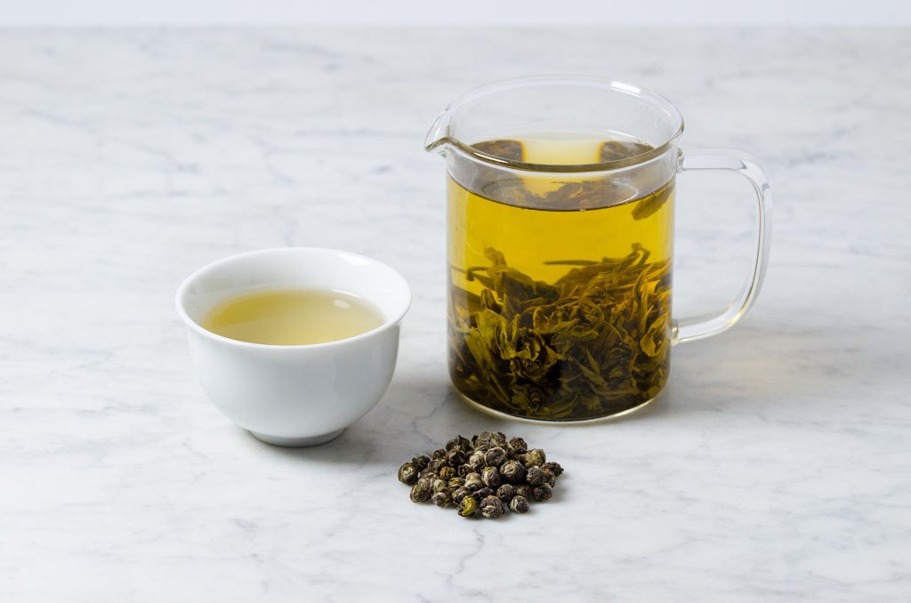 loose leaf jasmine green tea in a white cup and glass infuser