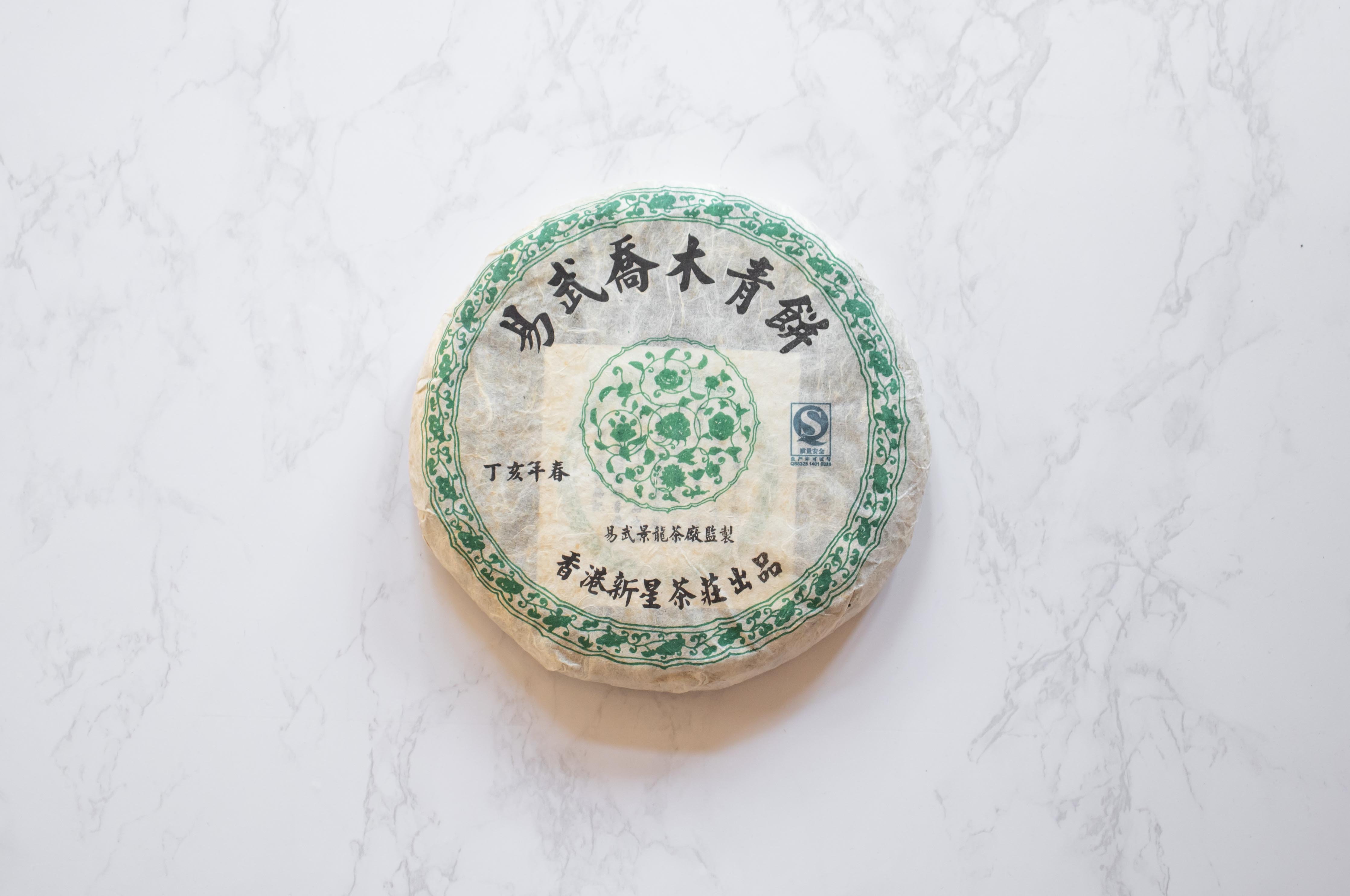 2007 Yiwu Jing Long sheng pu'er round aged tea cake wrapped in paper with Chinese characters.
