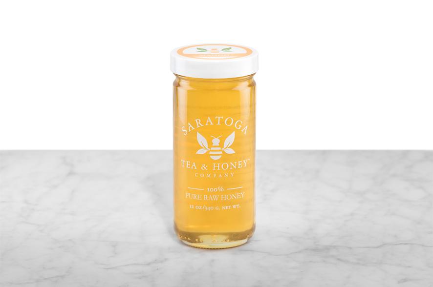 Golden Mango Infused Honey displayed in a 12oz cylindrical glass jar with a white lid. The logo and the words: "100% Pure Raw Honey" are printed on the jar.