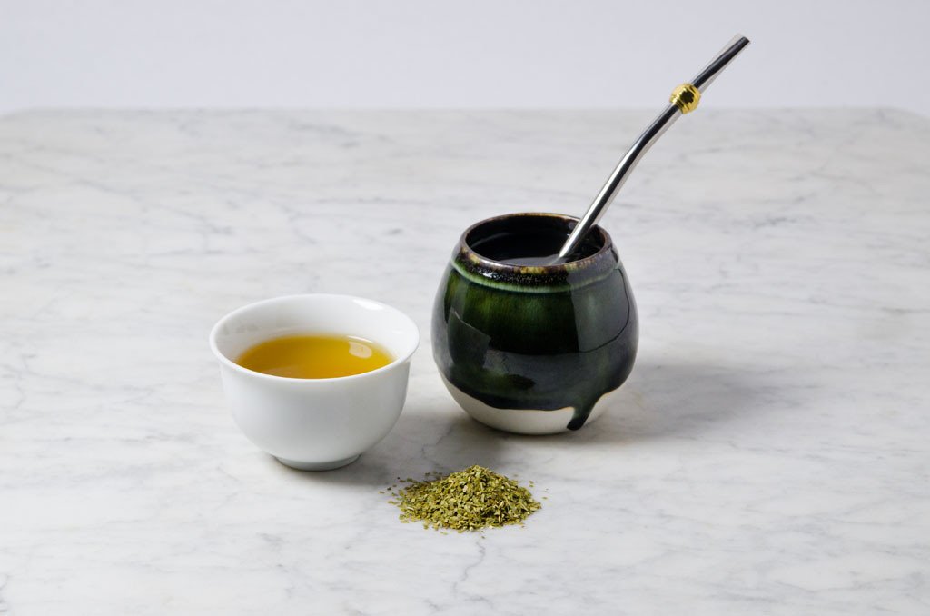 yerba mate served in a white cup and traditional mate gourd with bombilla