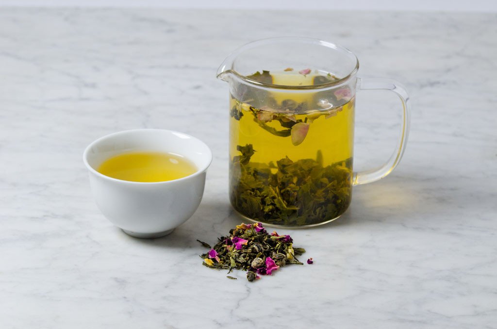 loose leaf rose and jasmine green tea infused in a glass infuser and poured in a white cup