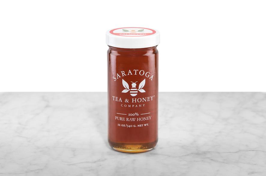 Dark amber Palmetto Honey displayed in a 12oz cylindrical glass jar with a white lid. The logo and the words: "100% Pure Raw Honey" are printed on the jar.