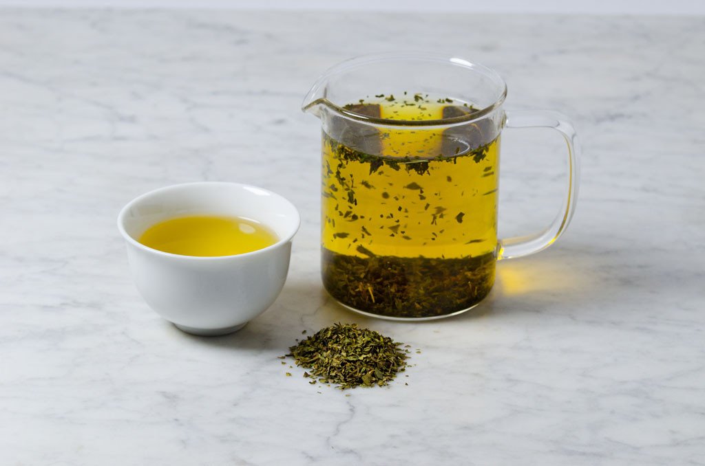 brewed peppermint tea in a white cup and glass infuser