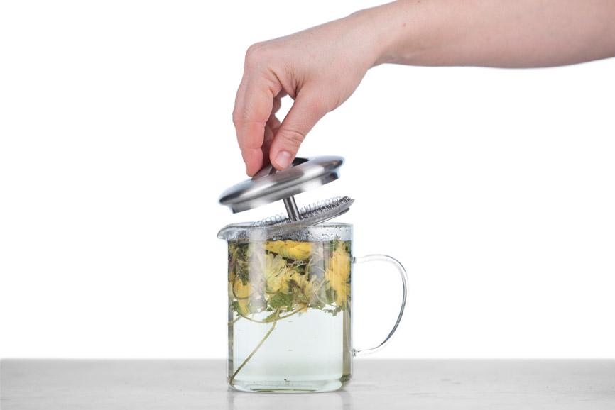 infusing a floral herbal tisane in a glass tea infuser