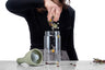 woman dropping full flower tisane into an iced tea brewing bottle