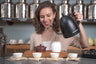 Hayley pours hot water over a small teapot to warm the vessel before traditional tea service.