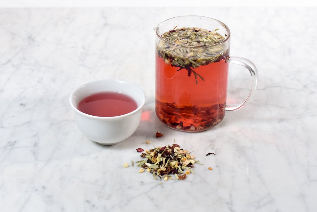 gorgeous fruit punch-colored herbal citrus tea in a white cup and glass infuser