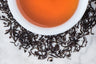 Italian Bergamot Scented Organic Black Tea Leaves Surrounding A Cup of Elegant Brewed Tea