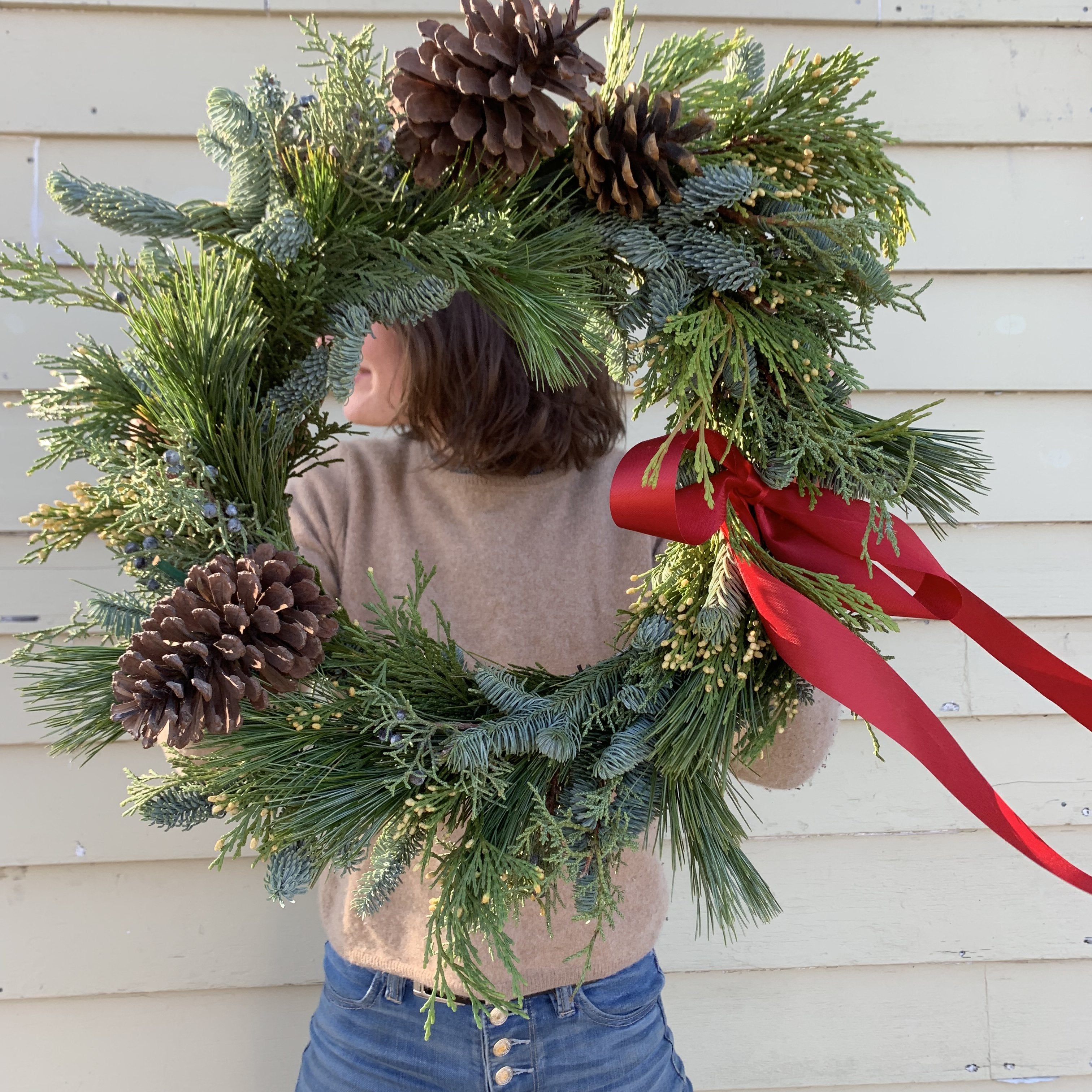brunette woman holding a homemade holiday wreath