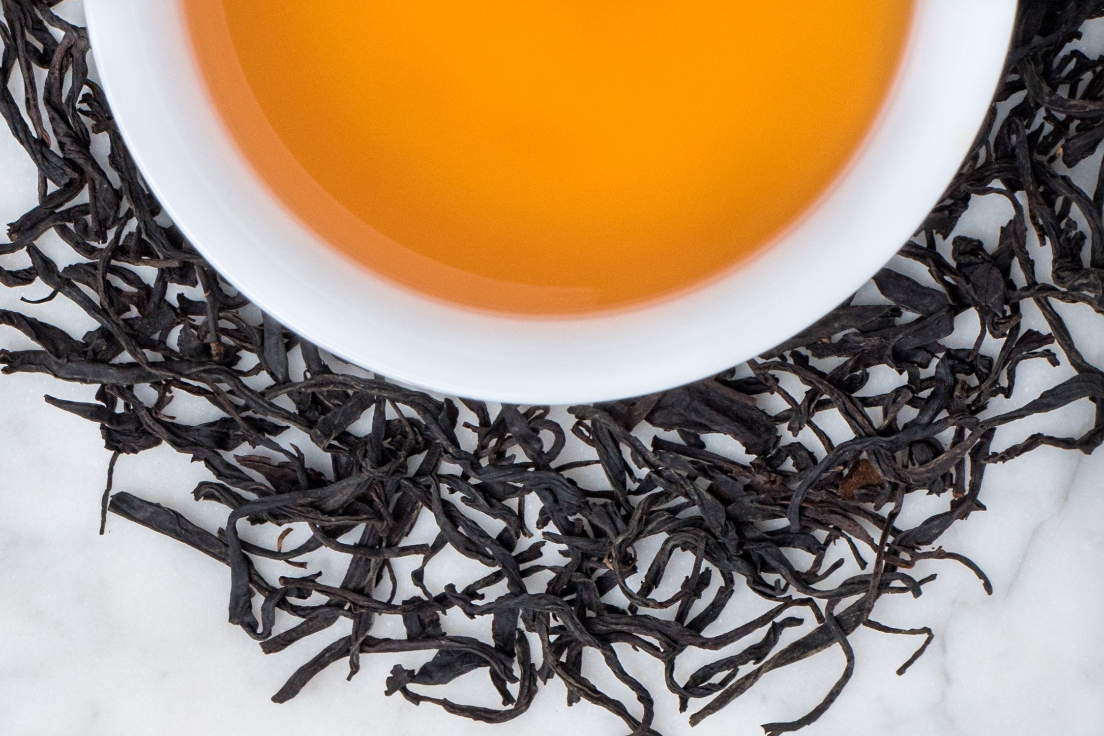 Long Twisted Graceful Leaves of Feng Huang Hong Cha Black Tea Hugging A Cup of Its Deeply Complex Tea Liquor