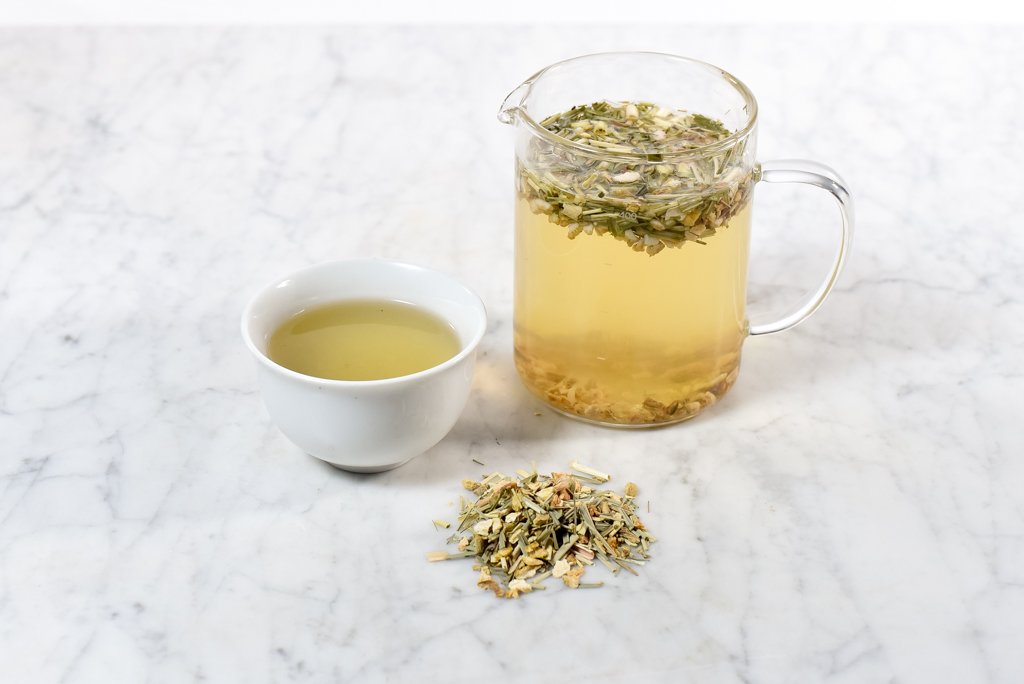 Spicy infusion of ginger and lemon in a white cup and glass tea infuser