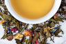 Sweet White Peach Tea Leaves Surrounding A Cup of Brewed Tea