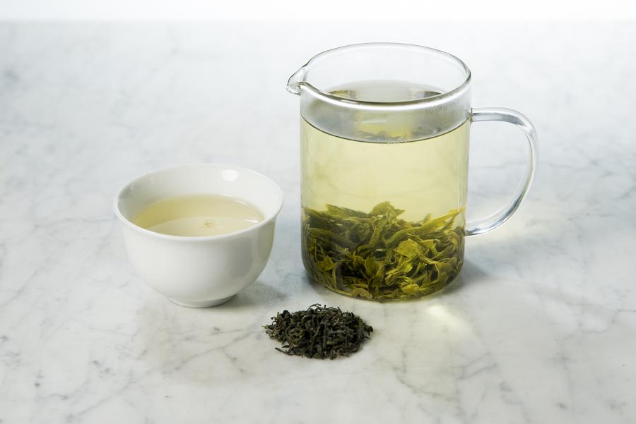 brewed loose leaf Vietnamese green tea in a glass infuser and white cup