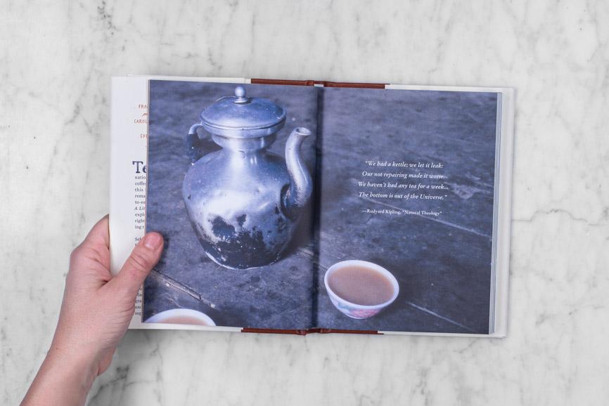 hand opening "A Little Tea Book" to a photo page with an out-of-focus quote