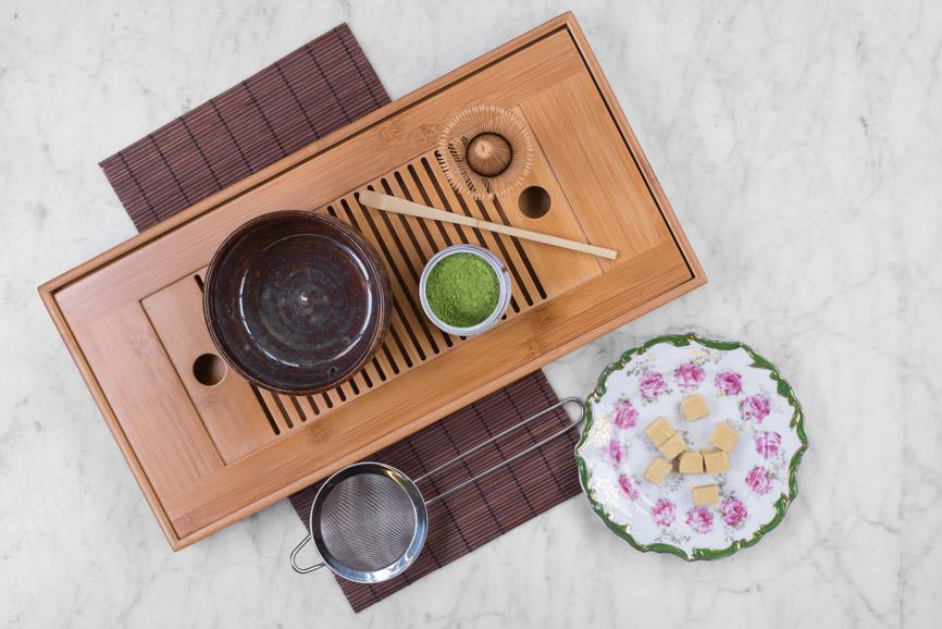 bamboo tea boat with a matcha set up: matcha bowl, tin of ceremonial matcha, bamboo scoop, and matcha whisk